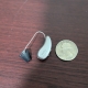 Signia Pure Charge&Go 5 ix in champagne on table next to quarter for scale